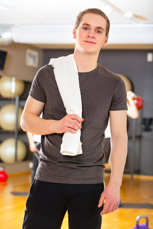 Confident and smiling young man exercising at fitness gym