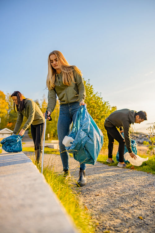 Young volunteers picking up garbage in bag at park