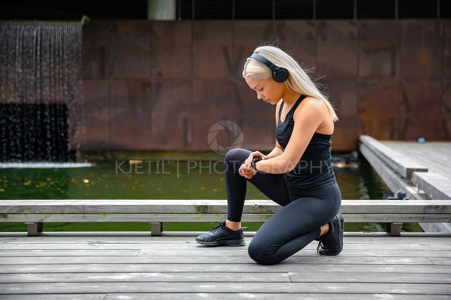 Sporty Female Runner Listening Music On Headphones and Using Smartwatch