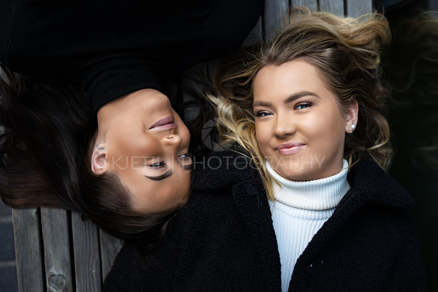 Portrait Of Two Smiling Best Friends Lying On Bench