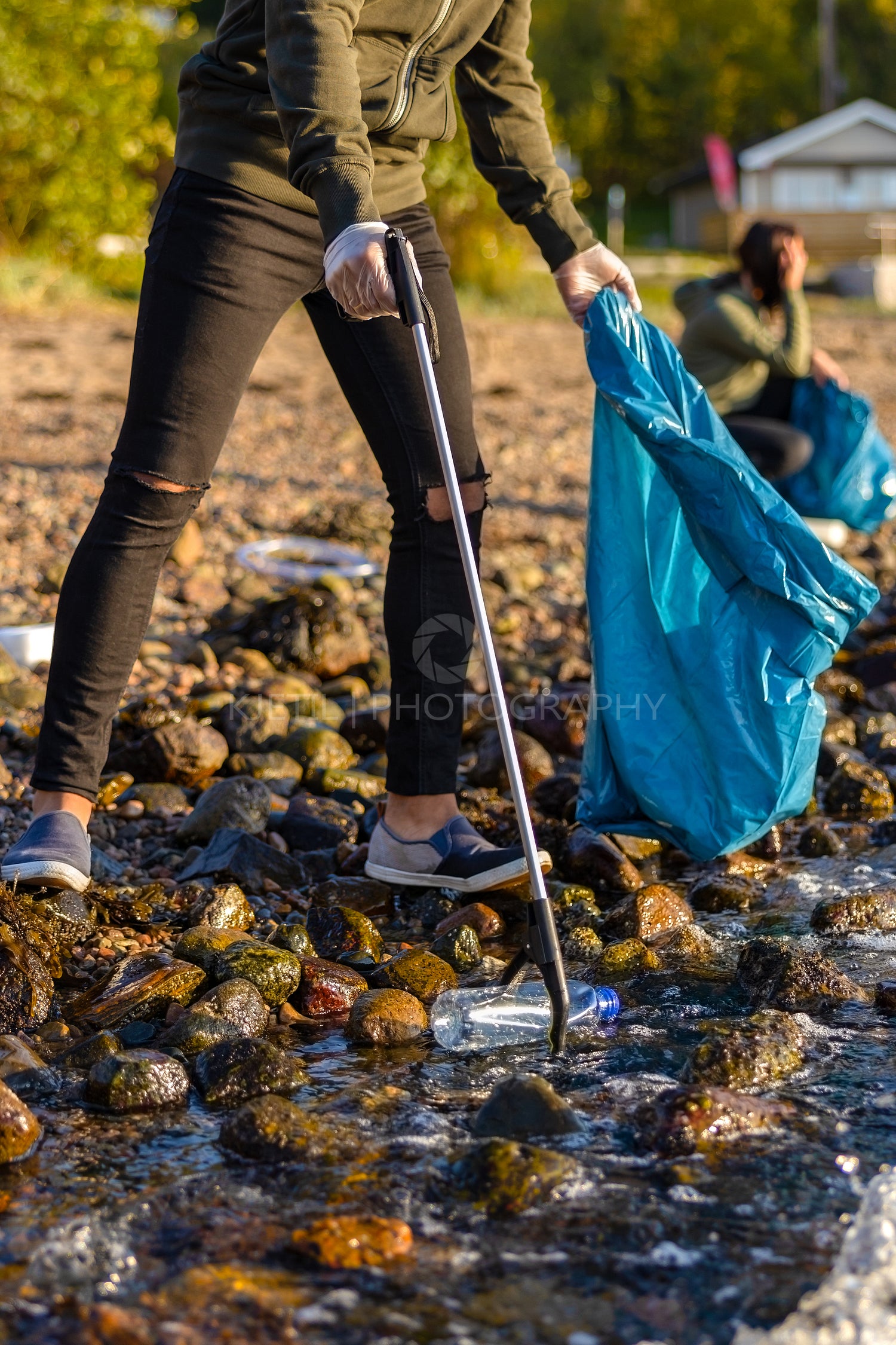 Close-up of volunteer picking up garbage with grabber at beach