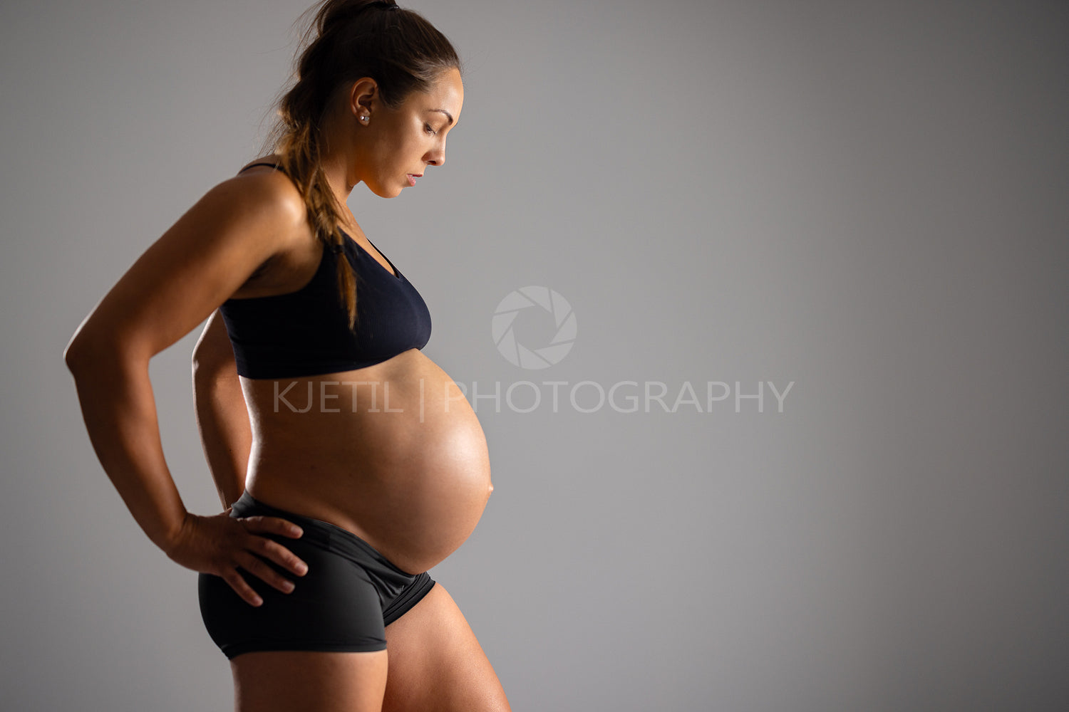 Pregnant woman with bare belly and hands on her hips