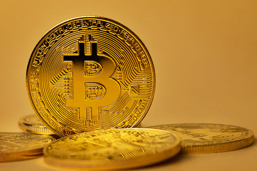 Closeup of shiny gold bitcoin on yellow backgound