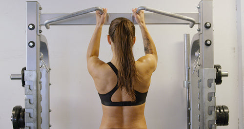 Hard training fitness woman doing heavy pull-ups in fitness gym