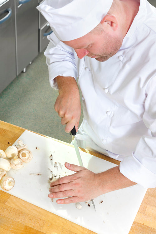 Professional chef preparing mushrooms in large kitchen