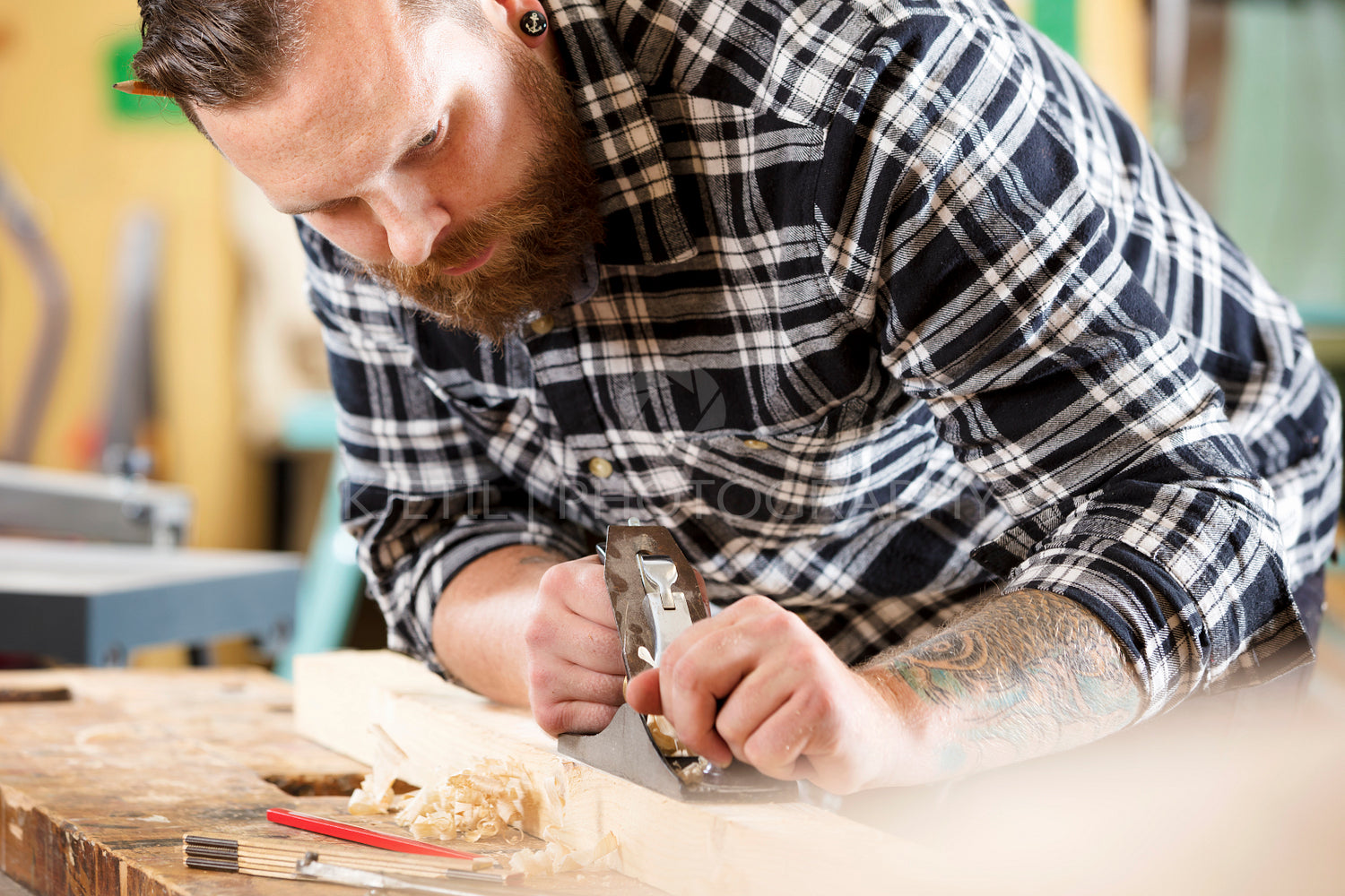 Carpenter work with plane on wood plank in workshop