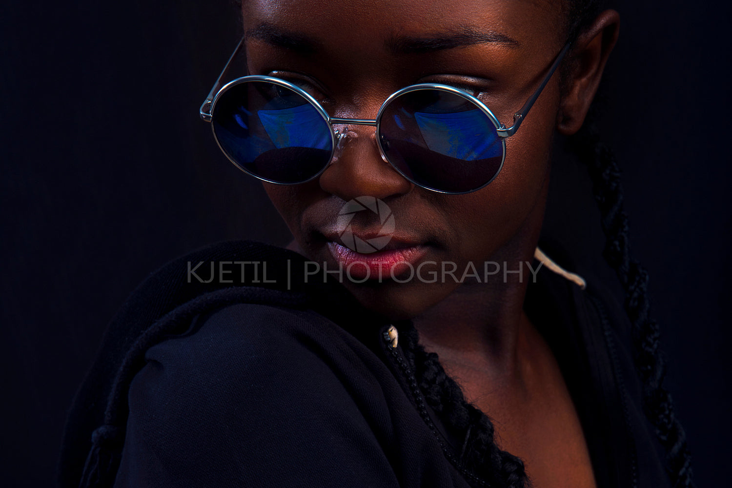 Close-up of woman with dark skin wearing round sunglasses