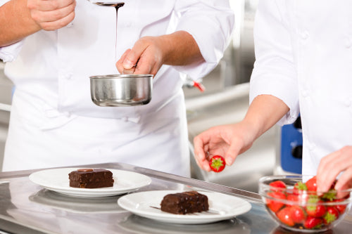 Chef decorates dessert cake with chocolate sauce in kitchen