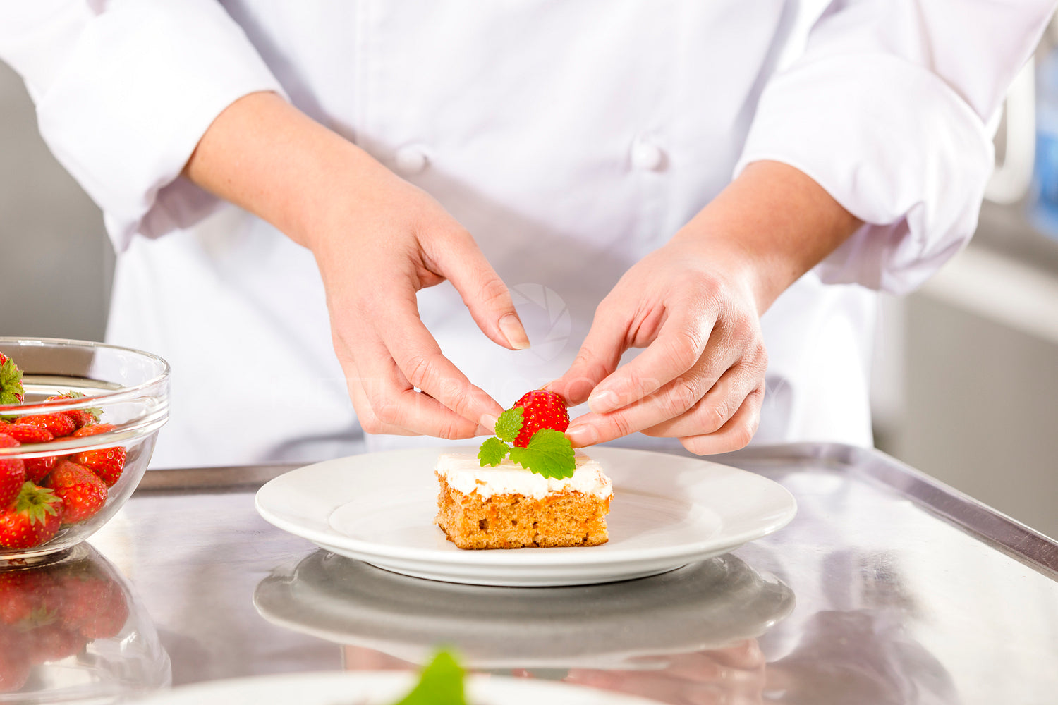 Close-up of chef decorating dessert cake with strawberry