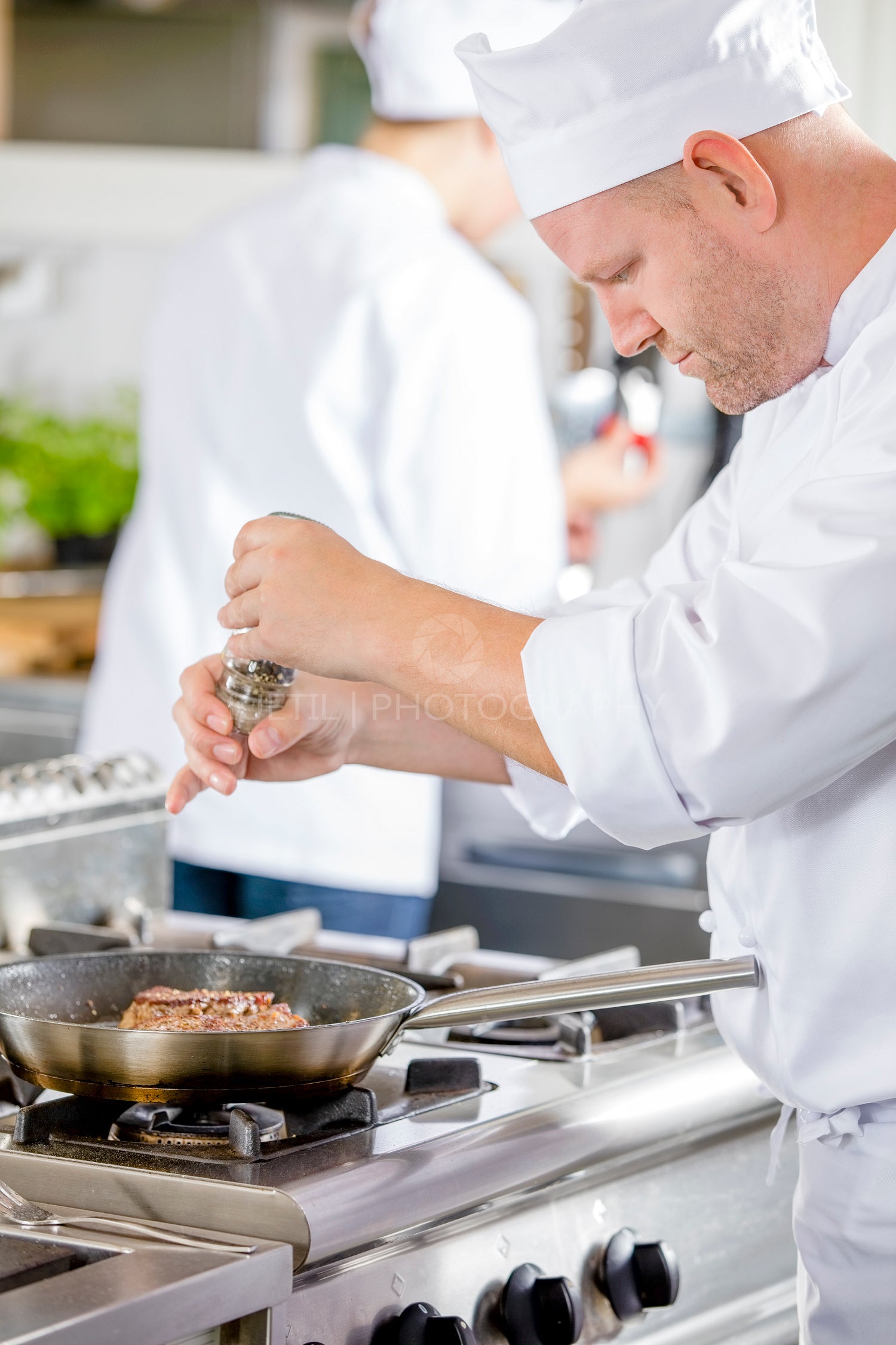 Chef prepares steak in pan at the kitchen