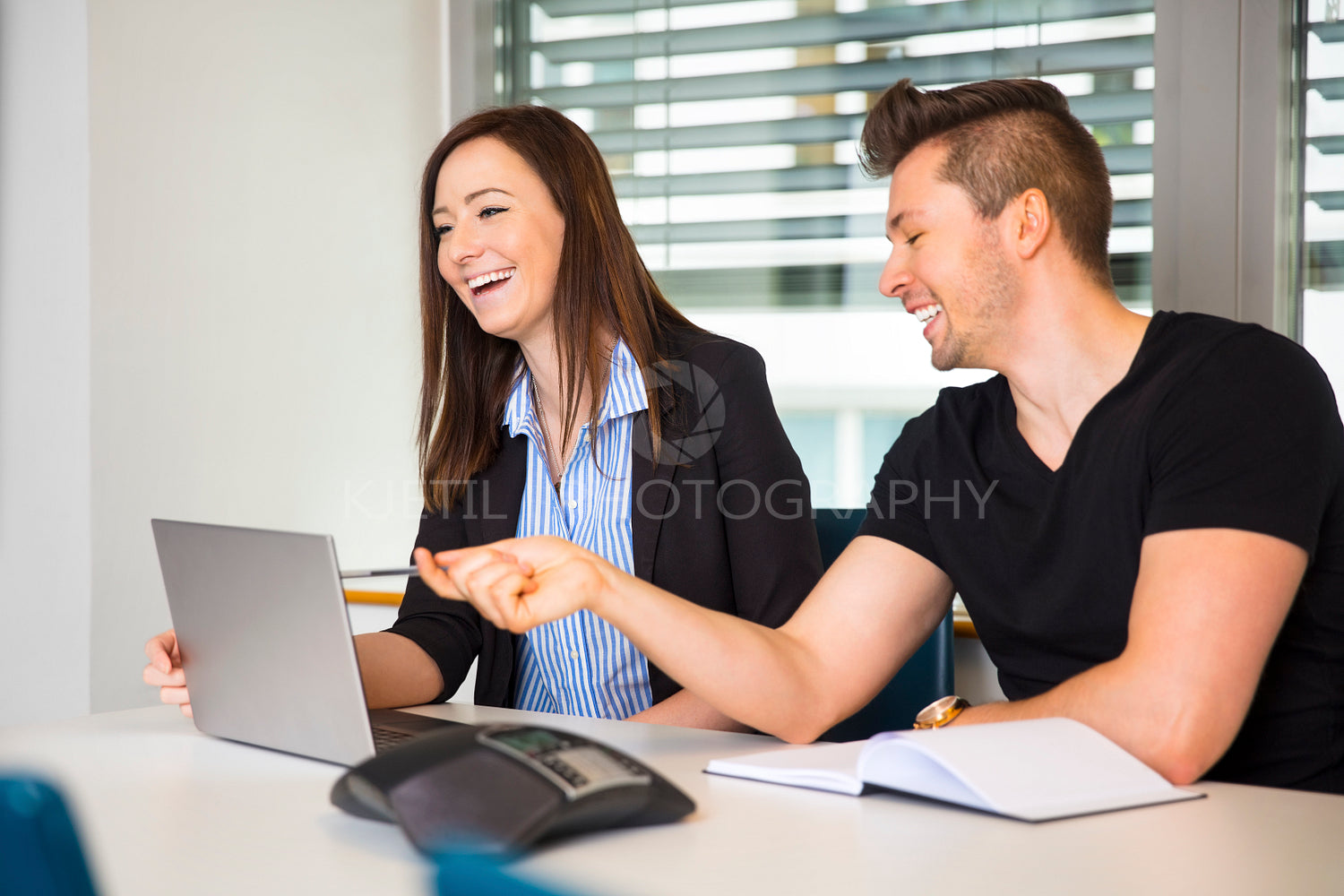 Smiling Business People With Laptop Communicating At Desk