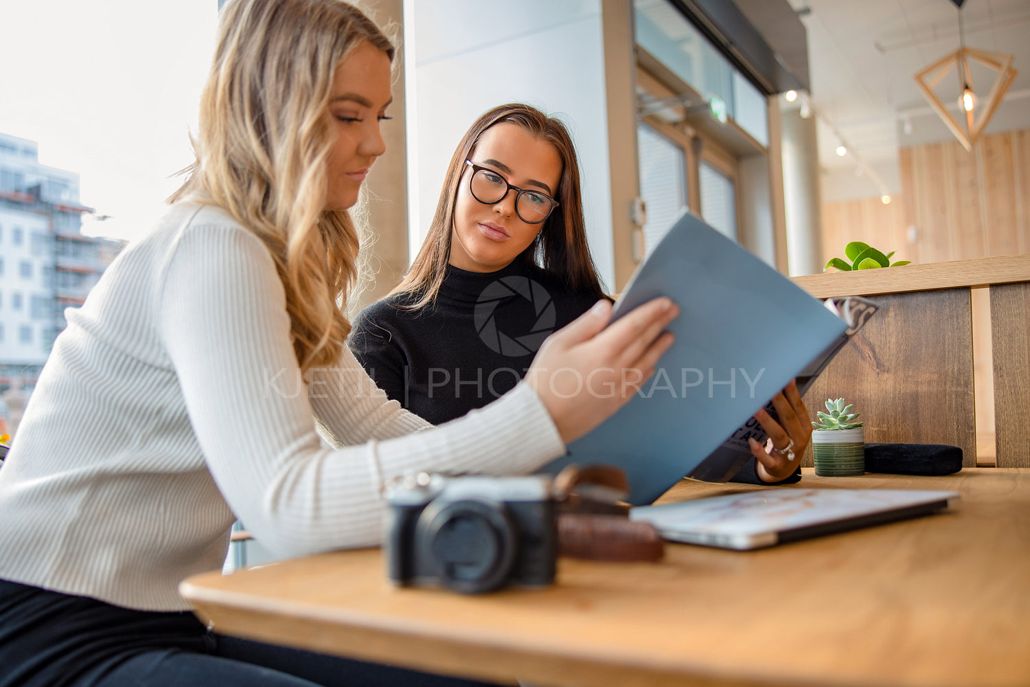 Two Female Bloggers Discussing Over Publication In Magazine Cafe