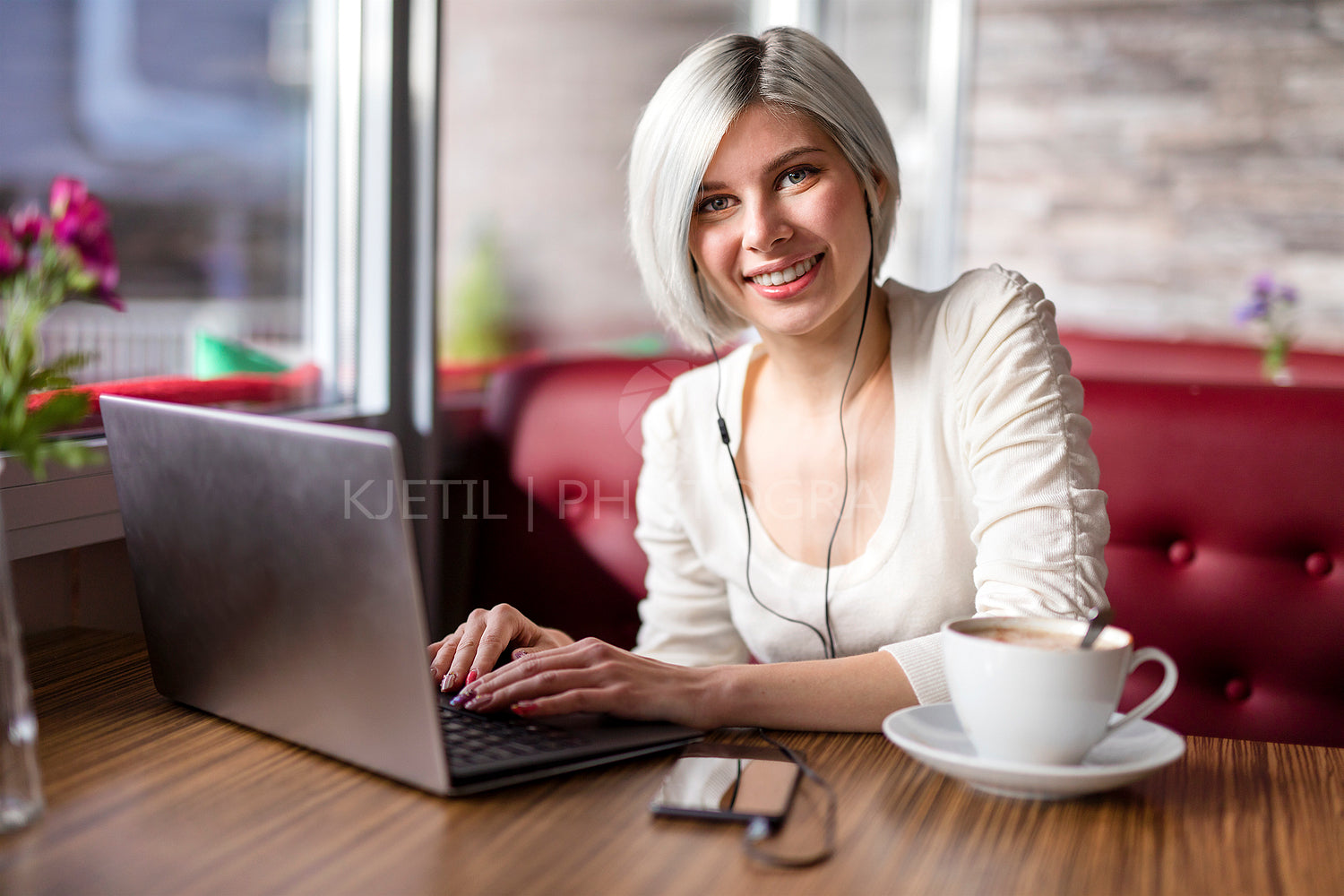 Cheerful woman working with laptop computer in cafe