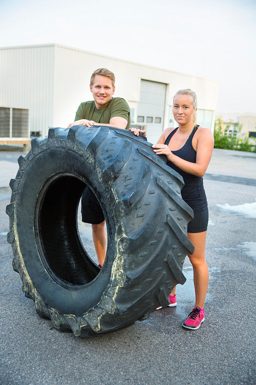 Confident Athletes Standing By Huge Tire Outside Health Club