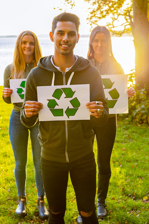 Group of volunteers holding recycling symbol placards
