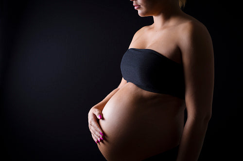 Pregnant woman with her hand on the bare belly