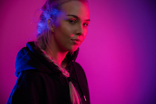 Colorful low-key portrait of a cool and confident blonde woman in hoodie