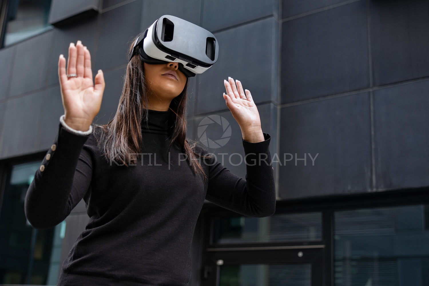 Woman Playing With Virtual Reality Glasses Against Futuristic Wall
