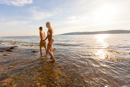 Young Couple Holding Hands Wading In Sea