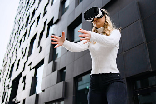 Woman Wearing VR Glasses In Front Of Urban Looking City Building