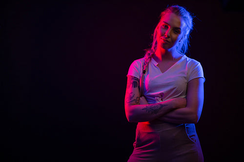 Colorful portrait of a confident blonde woman wearing white top on black backgound
