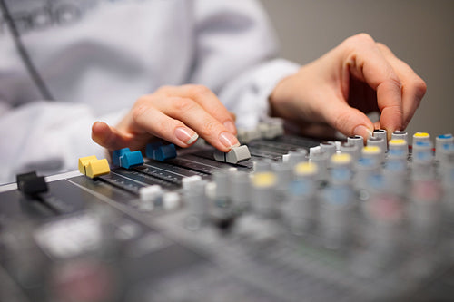Midsection Of Radio Host's Hands Using Music Mixer In Studio