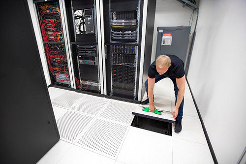 IT Engineer Lifting Floor Tile Using Suction Cups In Datacenter