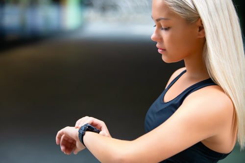 Profile of Female Runner Checking Smartwatch After Workout On Road