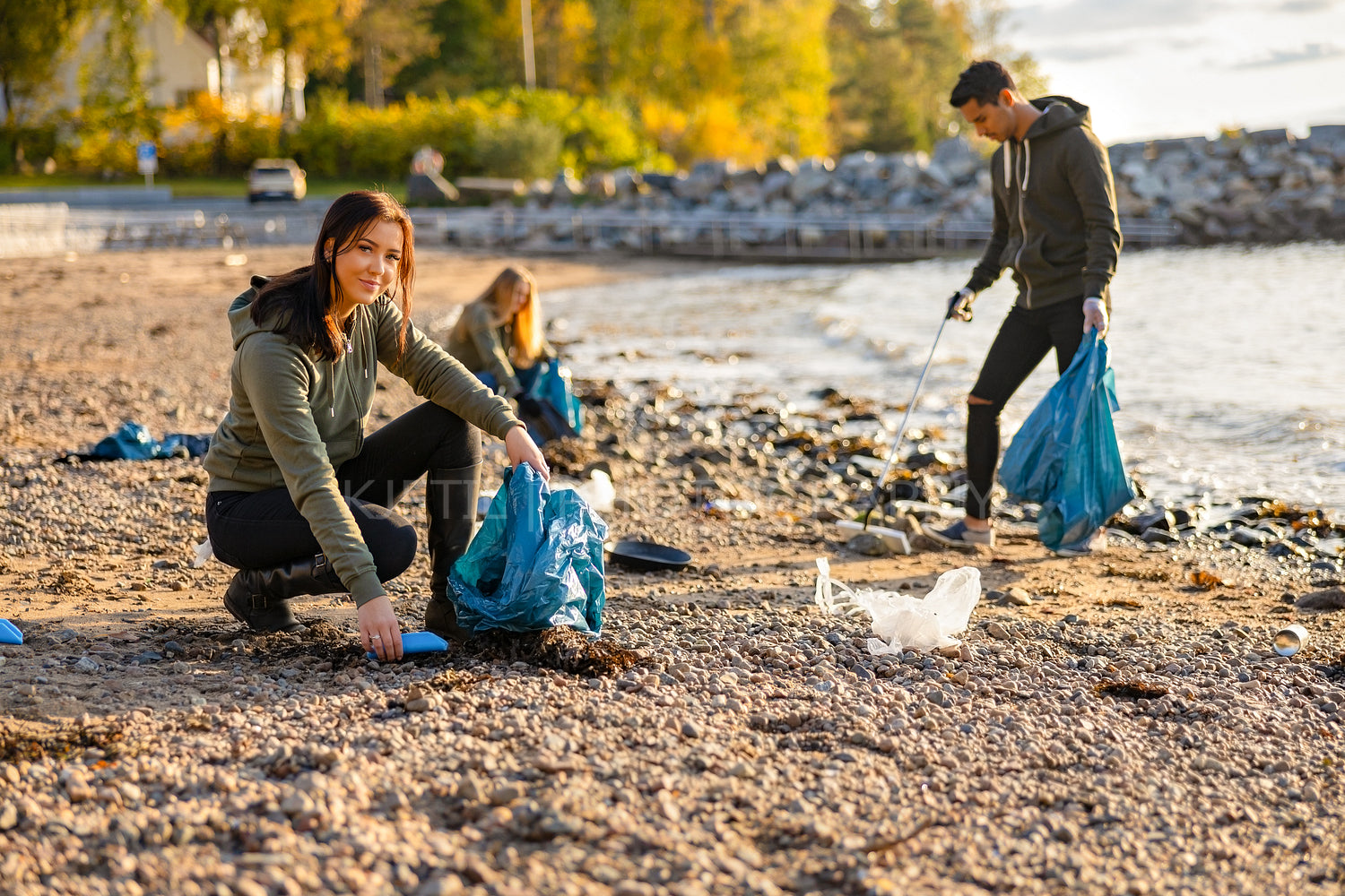 Young woman picking up garbage in bag at beach