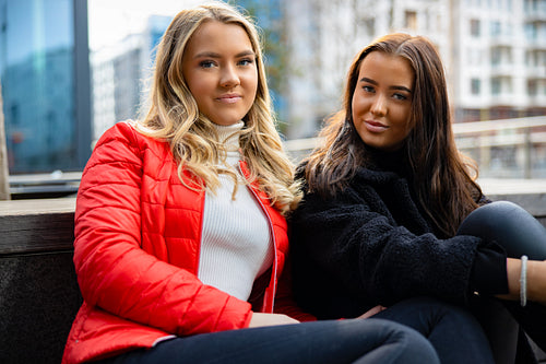 Portrait Of Two Smiling Female Best Friends Sitting In City
