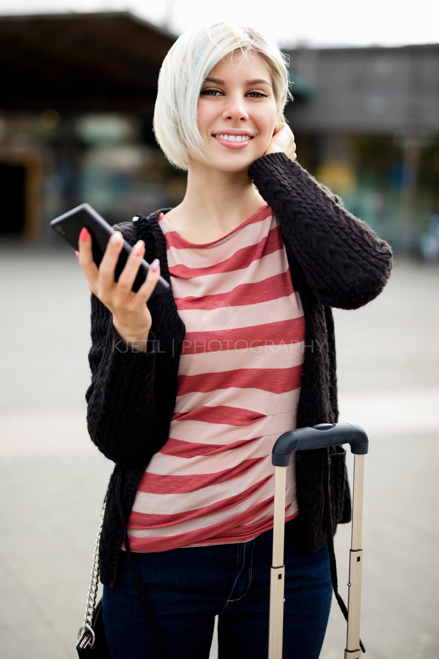 Smiling Young Woman Holding Smart Phone Outside Railroad Station