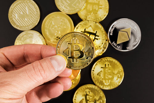 Hand of man choosing golden Bitcoin or BTC as preferred asset