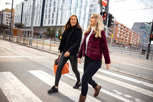 Female Friends Talking While Crossing City Street