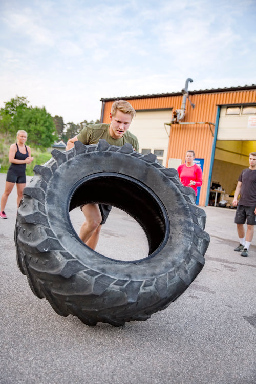 Strong man flips heavy tire outdoor as workout