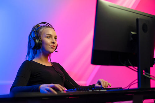 Happy Gamer Girl with Headset Playing Online Video Game on PC