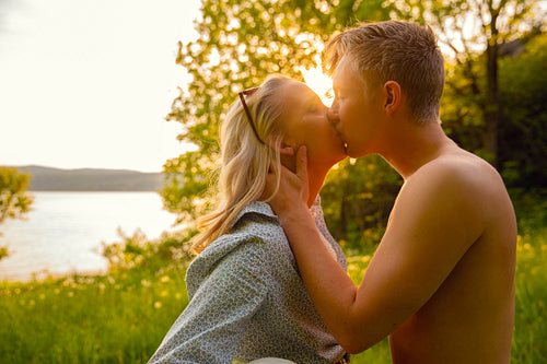 Young Shirtless Man Kissing Girlfriend During Sunset