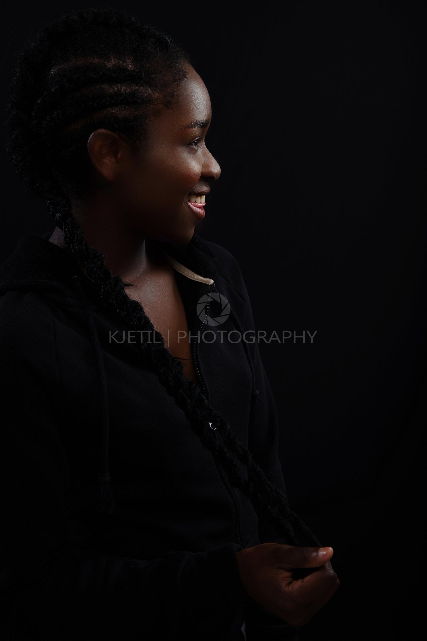 Natural woman with dark skin laughing and wearing black hoodie