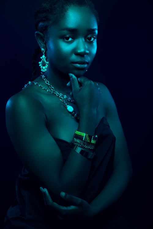 Blue toned portrait of sensuous woman wearing jewelry over red background
