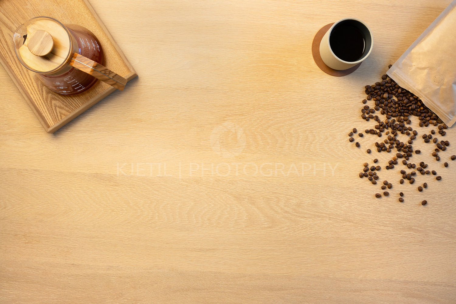 Overhead view of coffee pot and beans by cup on wooden table