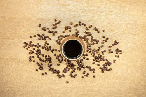 Overhead view of roasted beans and coffee in cup on table