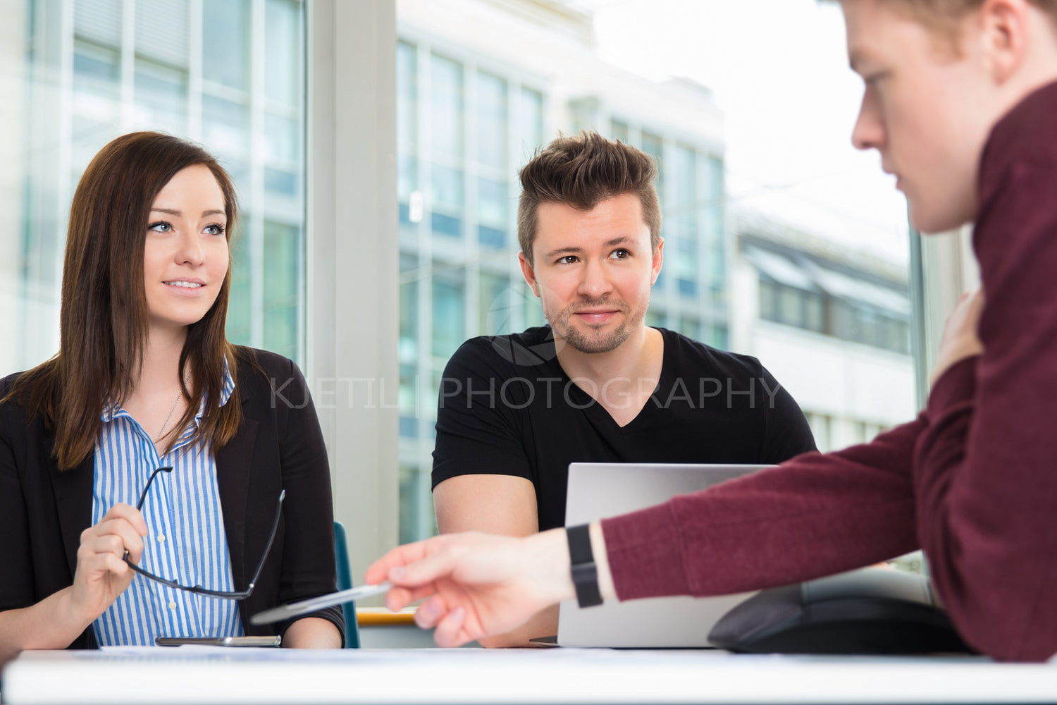 Business People Looking At Colleague Explaining At Desk