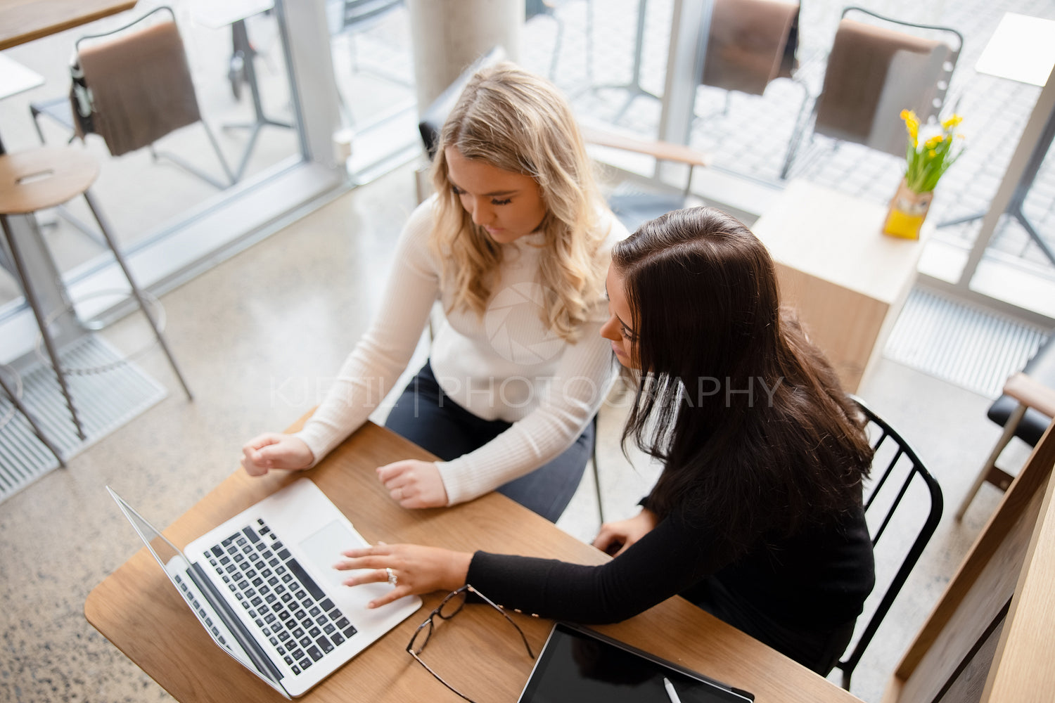 Top view of two women working on project at modern coffee shop in city