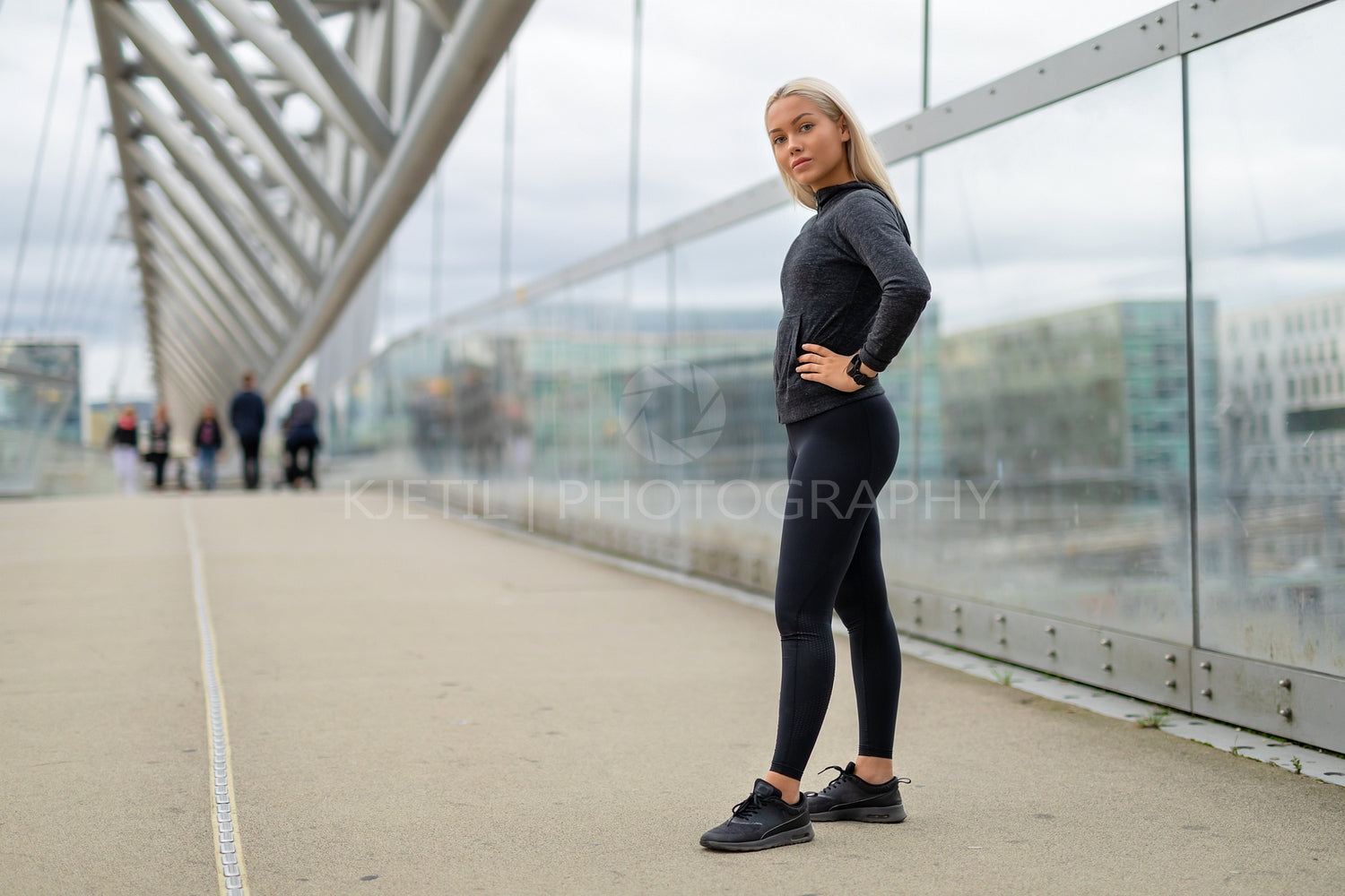 Fit Woman in Black Workout Outfit Standing At Modern Bridge In City