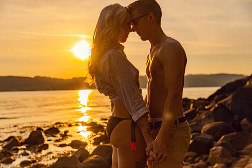Young Romantic Couple Holding Hands At Beach During Sunset