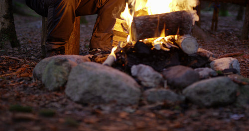 Man using compass and smart phone by campfire in the woods