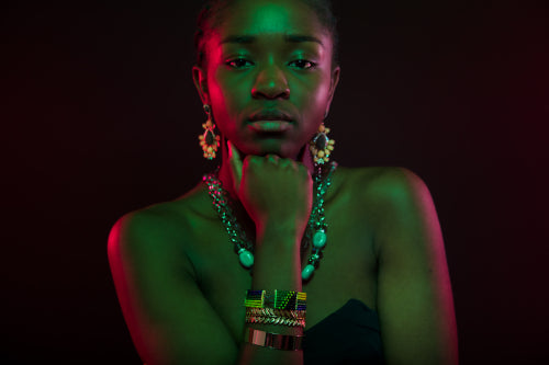Woman With Hand On Chin Wearing Jewelry Over Black Background