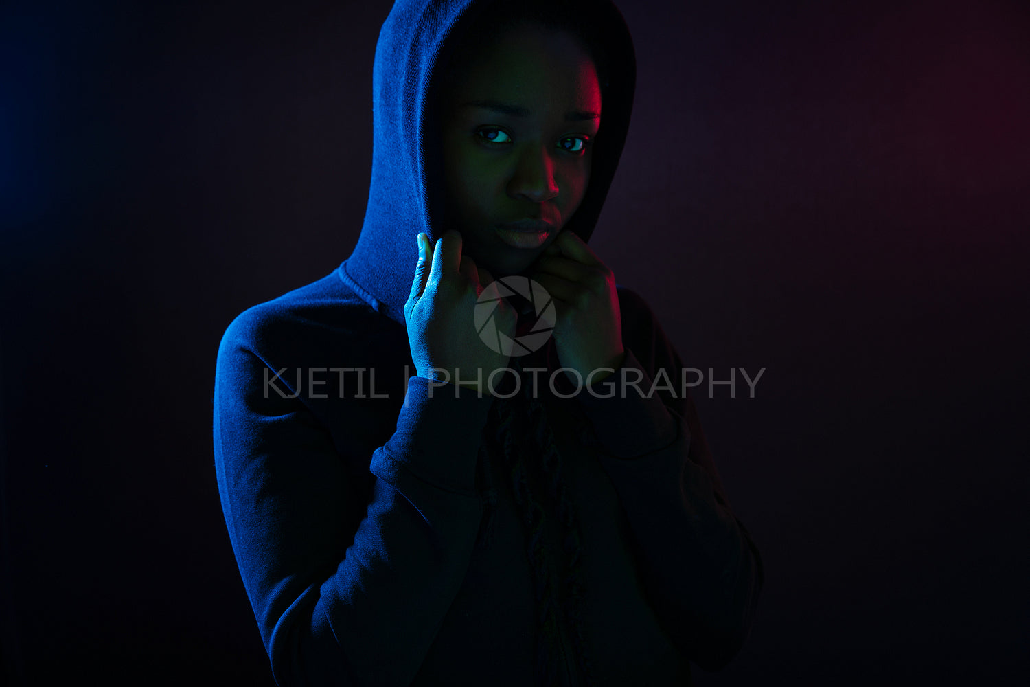 Dark colorful studio portrait of a cool black woman wearing hoodie