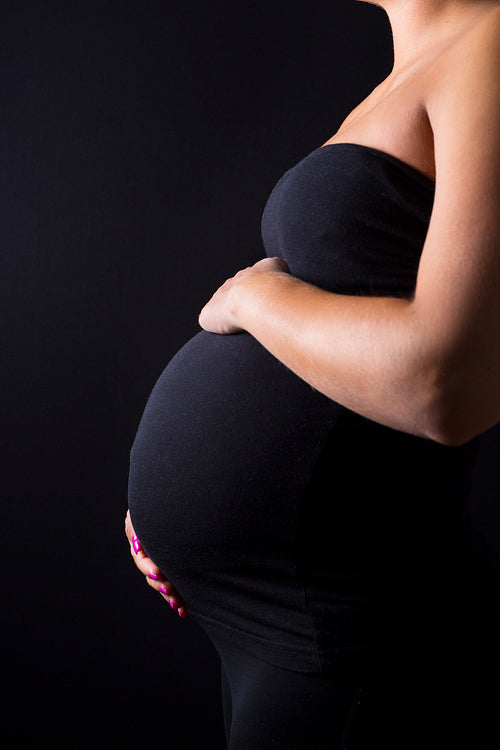 Pregnant woman stand with hands at the belly