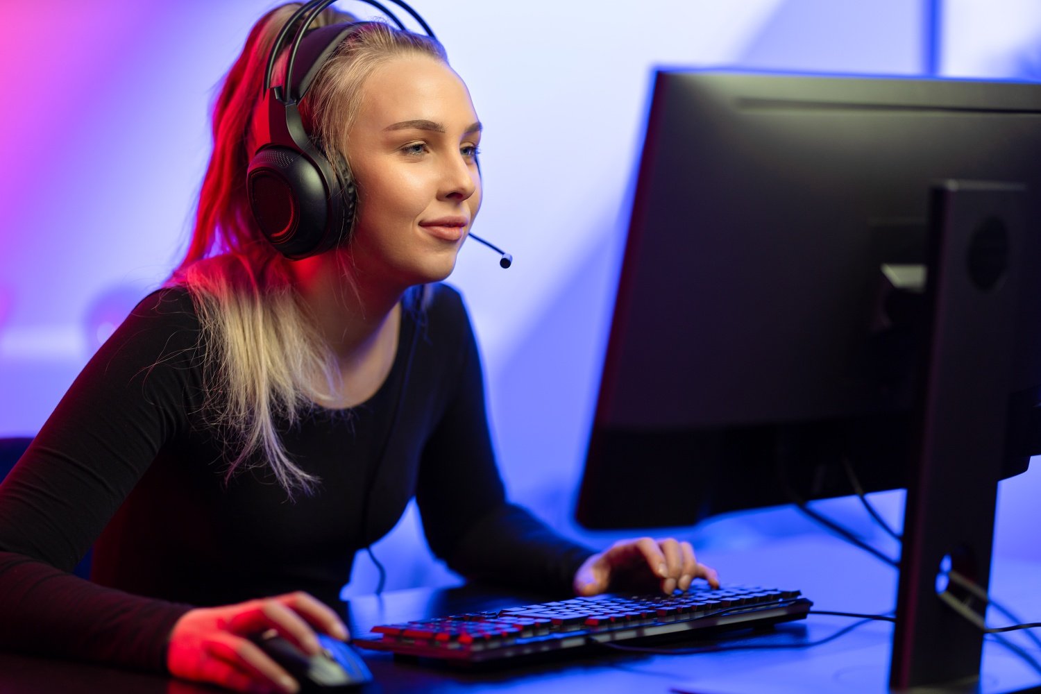 Focused E-sport Gamer Girl with Headset Playing Online Video Game on PC