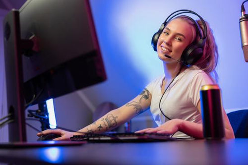 Smiling e-sport gamer girl vlogging and plays online video game on PC